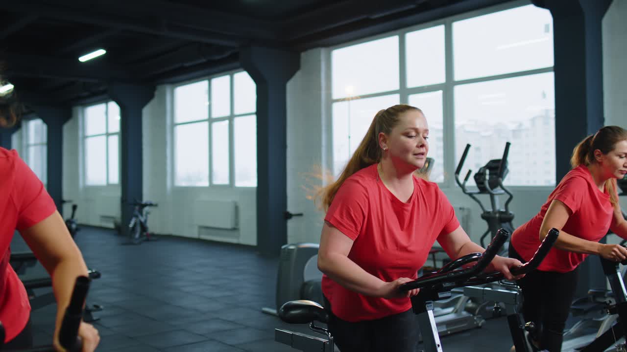 Gruppo di ragazze esegue un allenamento cardio aerobico su cyclette, allenamento ciclistico.