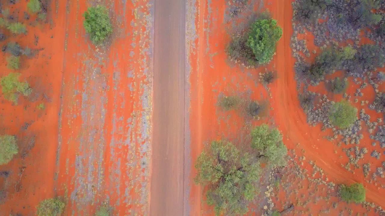 The Central Australian Outback. Top down shot, over roads, local flora and settlements, with tilt up to reveal low ridge. Filmed on a DJI Mavic Pro on a Camel Farm near Alice Springs.