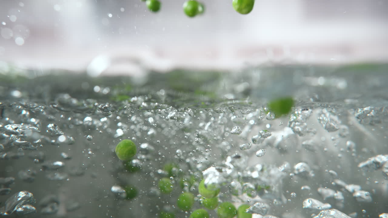 초록 콩은 는 물의 비에 떨어지고 뜨거운 물, 매크로 및 느린 모션에 가라앉습니다.