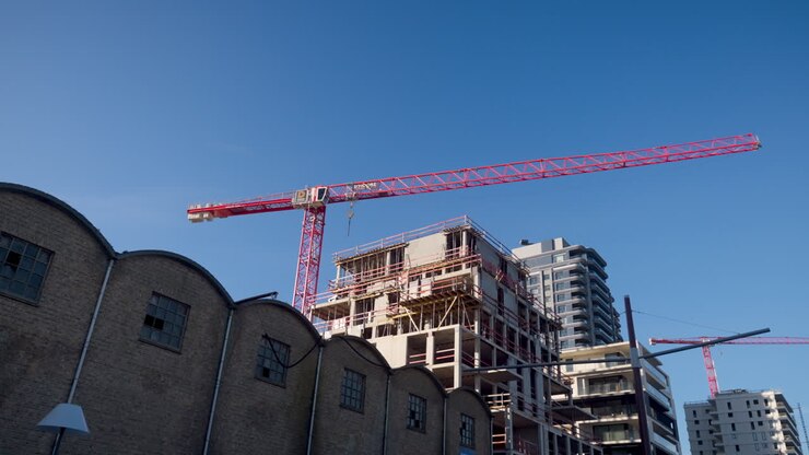 A tall crane working on new apartment buildings under the clear blue sky