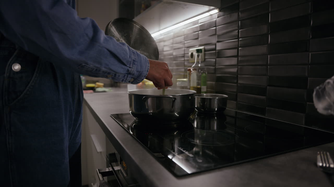 Girl holds the lid of a pot and checks the food on the stove using a fork, steaming hot boiling tasty meal, preparing dinner, cooking in the kitchen, stainless steel pot, stir, eating at home, health