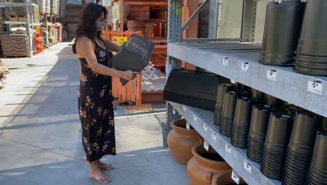 female wearing protective corona virus mask checking planters in home depot garden centre