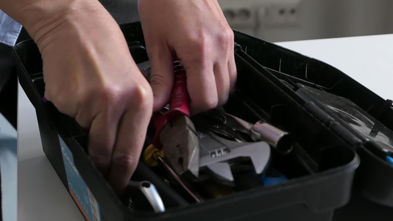 mujer tomando una llave ajustable de la caja de herramientas, eligiendo herramientas de la caixa de herramientas