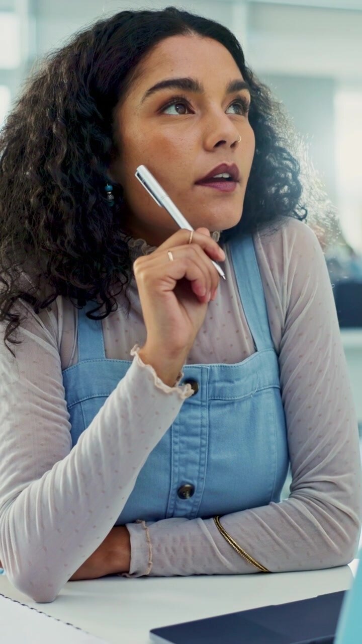 Young Woman Thinking and Working on Laptop in Office