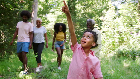 Niño-Caminando-Delante-De-Una-Familia-Negra-De-Varias-Generaciones-En-El-Bosque