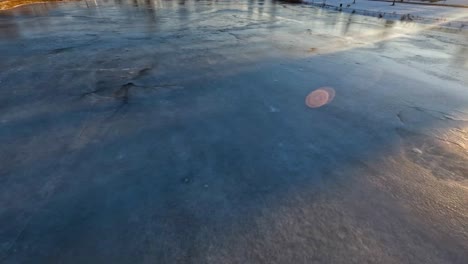 drone rápido volando sobre un estanque congelado en michigan durante la puesta de sol