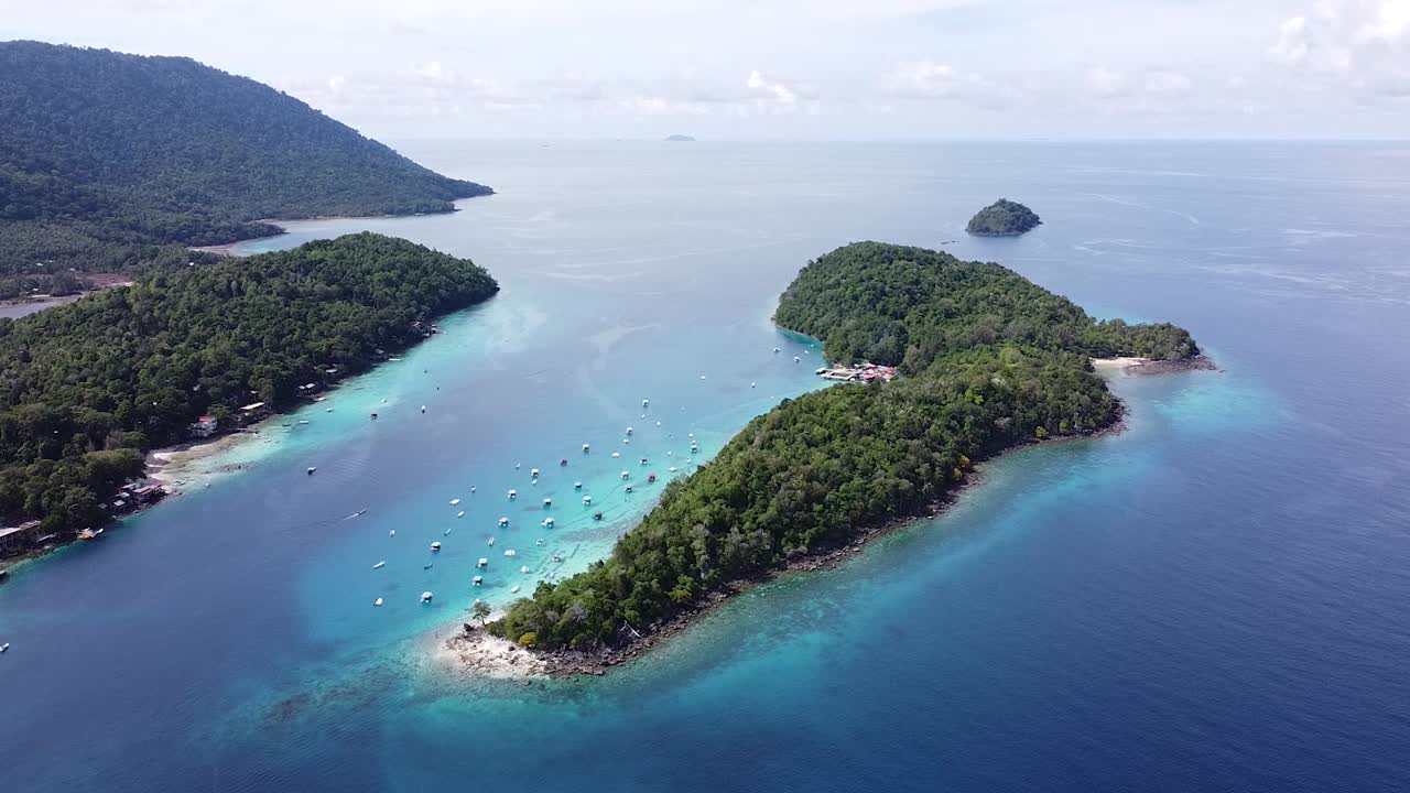 Scenic aerial view of tropical island of Pulau Rubiah in Pulau Weh Sabang Indonesia with docked tour and fishing boats and turquoise ocean water