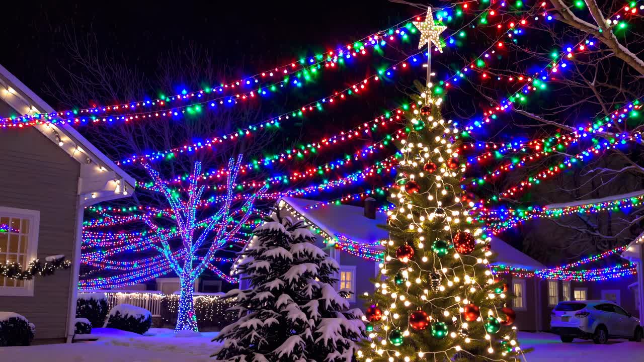 Festive Christmas lights adorn snowy houses and trees. Captured from a low angle, this vibrant scene