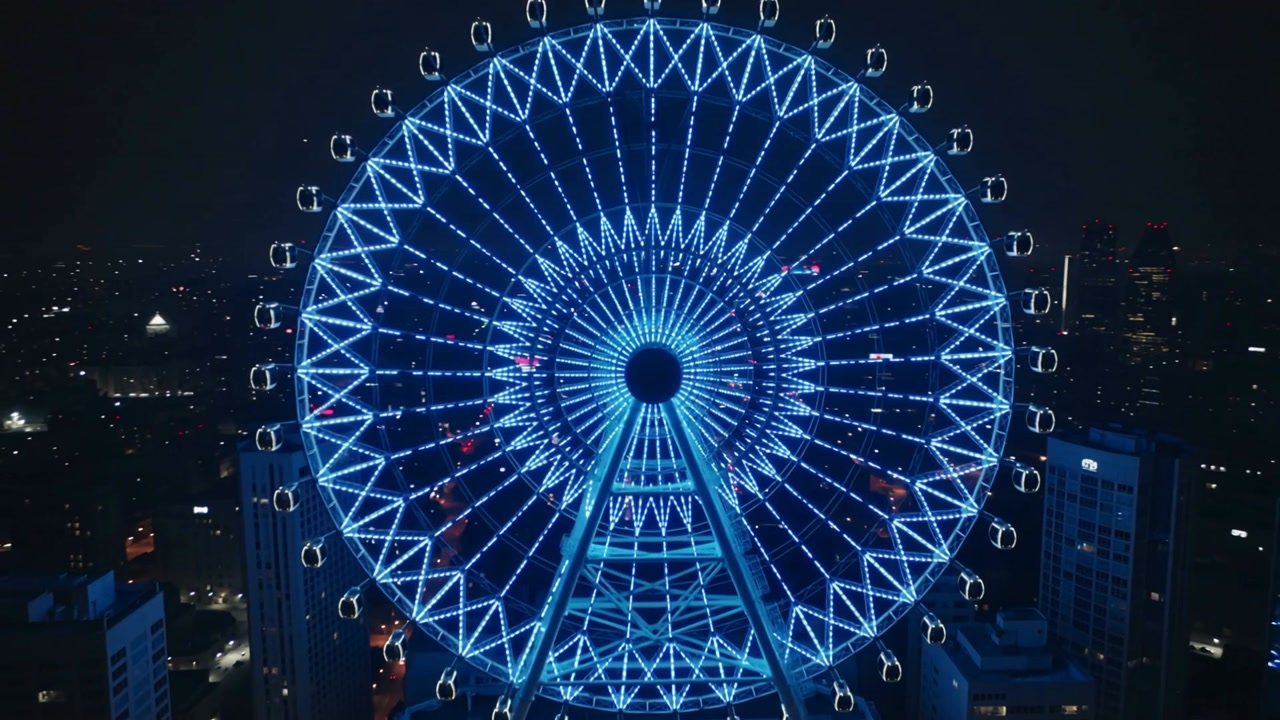Lit wheel rotating clockwise over city, motor powering blue LED ring, gondolas shifting for travel