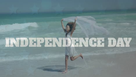 Animation-of-independence-text-over-african-american-woman-with-scarf-enjoying-at-the-beach