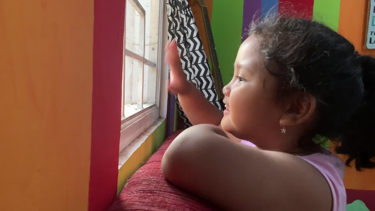 hermosa niña asiática sonriendo y agitando su mano por la ventana