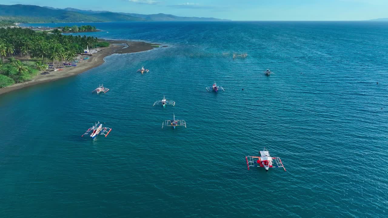 Aerial drone flight over coastline of Sarangani with beach and traditional bangka, fishing boats in south Philippines