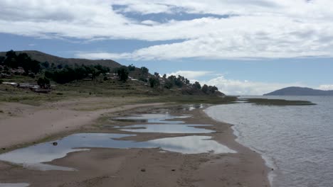 Low-drone-shot-tracking-forward-along-a-beautiful-sandy-beach-in-the-Titicaca-Lake