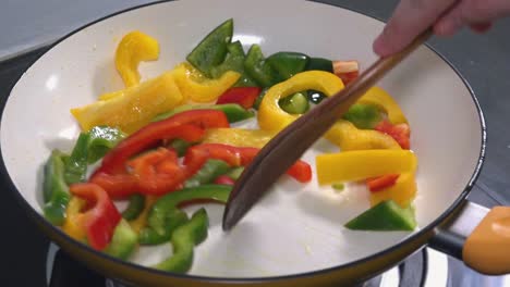 stir frying red green and yellow peppers in a frying pan