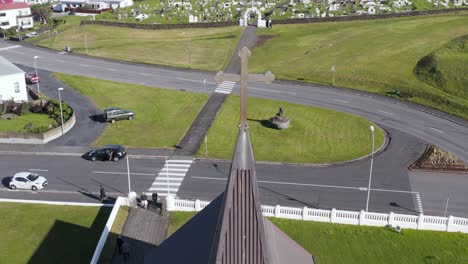 Landa-Church-bell-tower-with-steel-cross-in-small-Nordic-town,-aerial