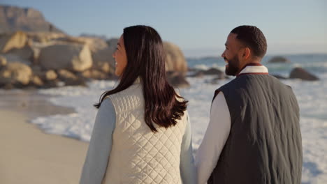 walking, beach and couple holding hands by ocean