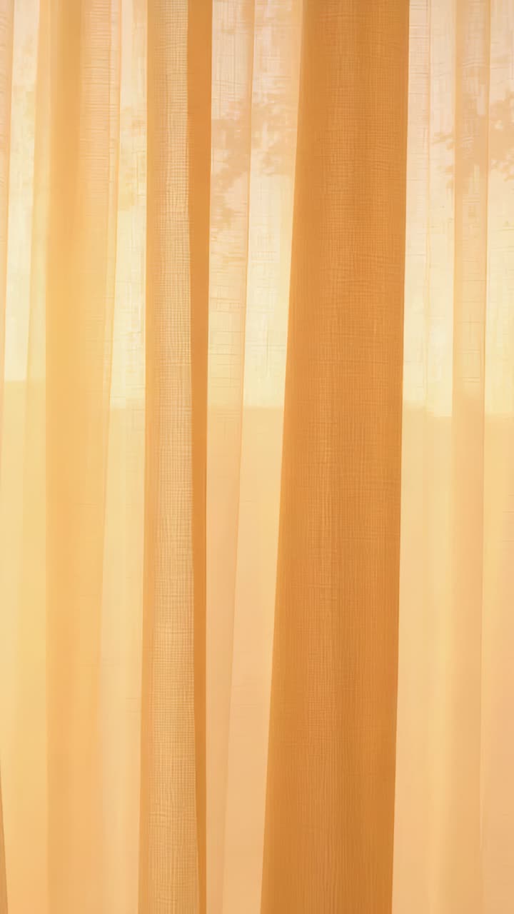 Vertical video: Shifting sheer panels showing amber glow at home, darker drape and tree branches