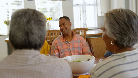 Vista-Frontal-De-Una-Familia-Negra-De-Varias-Generaciones-Comiendo-En-Una-Mesa-De-Comedor-En-Una-Casa-Cómoda-4k