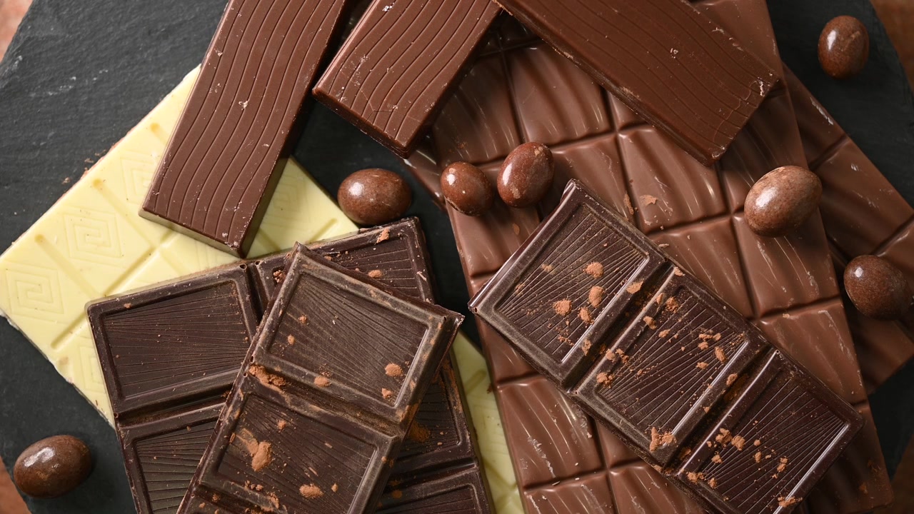 Hånd vælger stykker af mørk og lys chokolade fra et varieret sortiment