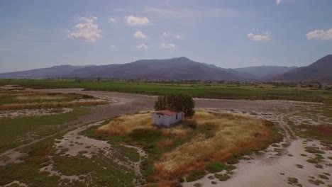 Aerial:-A-river-delta-with-a-road-bridge-passing-through-and-some-agricultural-buildings