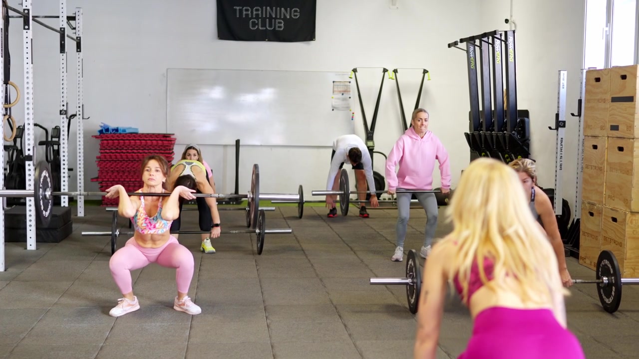 Gruppo di persone che eseguono l'esercizio di Clean and Squat con bilanciere in palestra