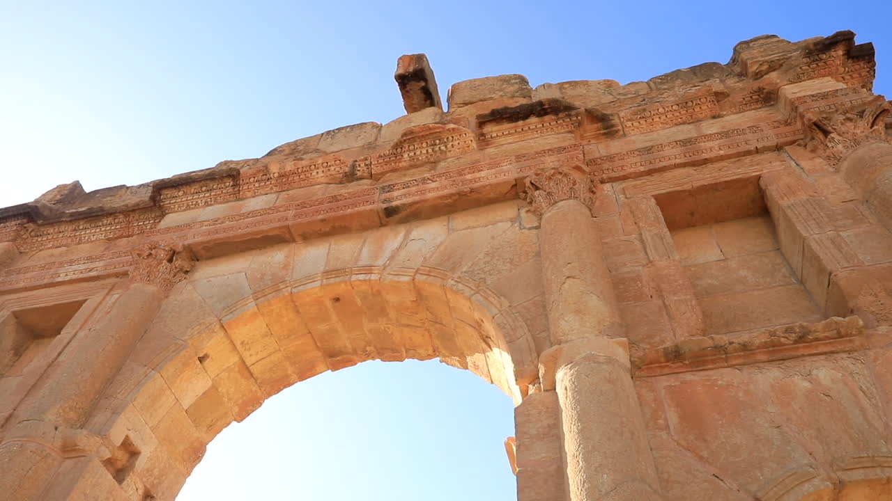 la luz del atardecer bañando el arco de las antiguas ruinas romanas de sbeitla en túnez, cielo despejado