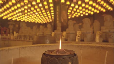 a panoramic view of a serene temple hall on miyajima island, japan, glowing with lantern light and rows of buddha statues.