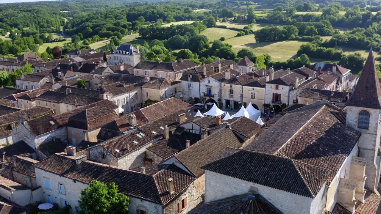 La chiesa e la piazza di Monpazier durante un evento culturale, stand bianchi per gli espositori sono al centro della piazza, Dordogna, Francia