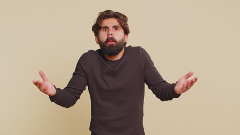 confused man raising hands asking reason of failure demonstrating disbelief on beige background
