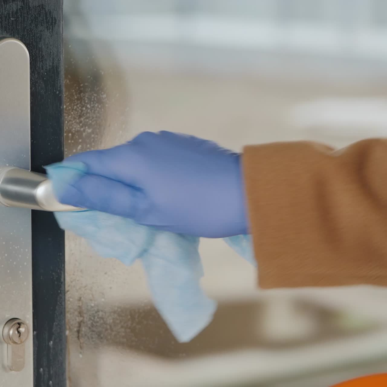 una mano en un guante protector en el mango de la puerta principal