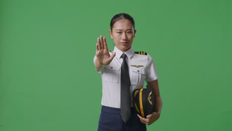 asian woman pilot looking at camera and disapproving with no hand sign in the green screen background studio