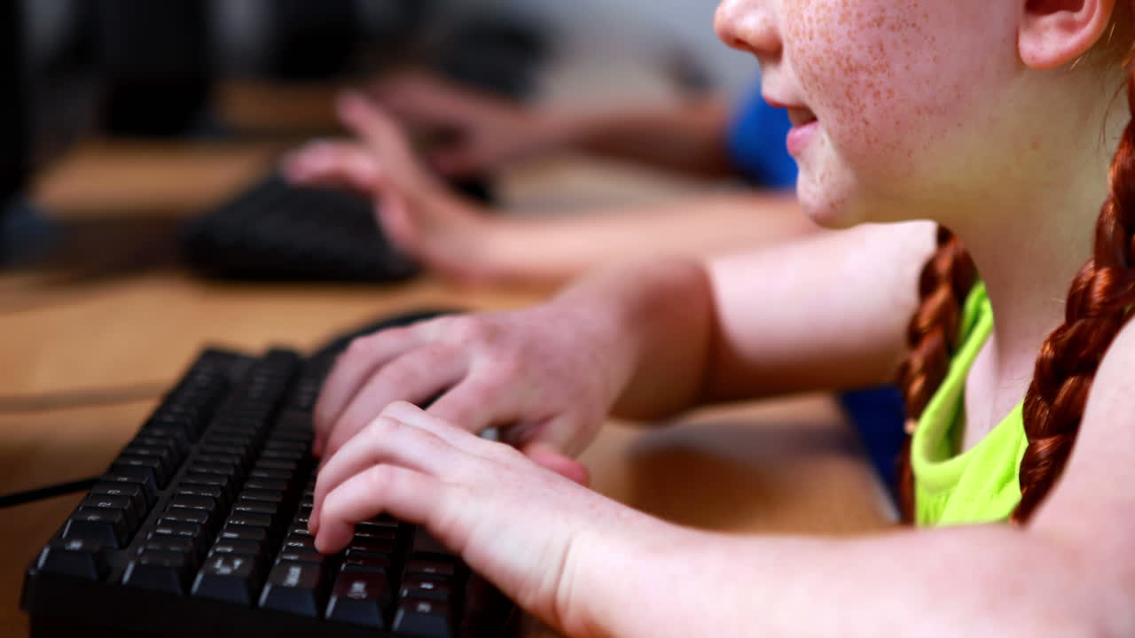 Little girl typing on keyboard and smiling at camera