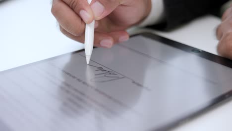 close up businessman hand working electronic signature on tablet by stylus. write business agreement of contract. man signing contract on tablet. business and technology concept.