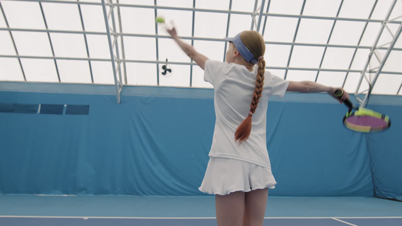Little Girl Hitting Tennis Ball On Court