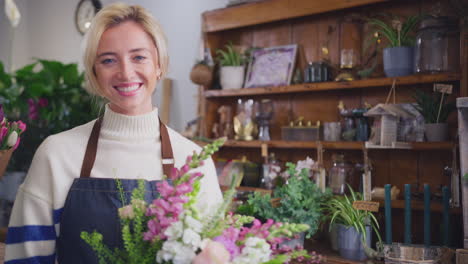 Portrait-Of-Female-Owner-Of-Florists-Shop-Holding-Bouquet-Of-Flowers