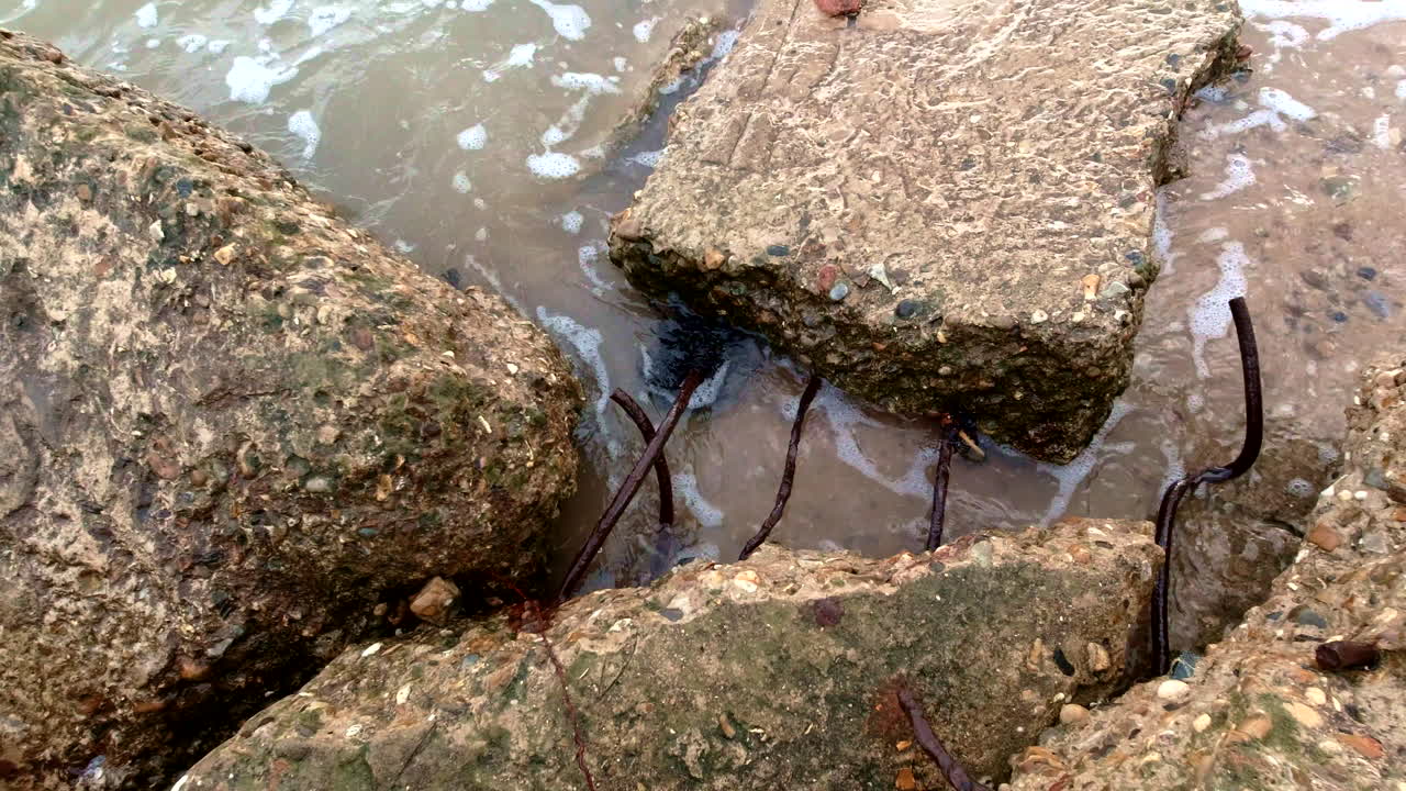 defensas marinas rotas entre las olas en la orilla de la playa a la luz del sol, disparo de cerca