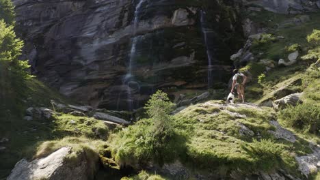 un hombre con su perro de pie frente a una cascada