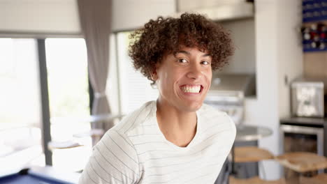 a young biracial man is smiling broadly in the kitchen at home
