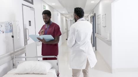 Focused-diverse-male-doctors-talking-and-female-nurse-with-wheelchair-in-slow-motion,-unaltered