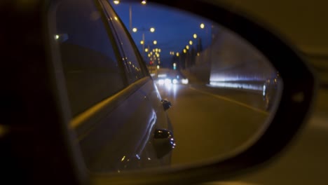 autos reflectantes en el espejo lateral por la noche