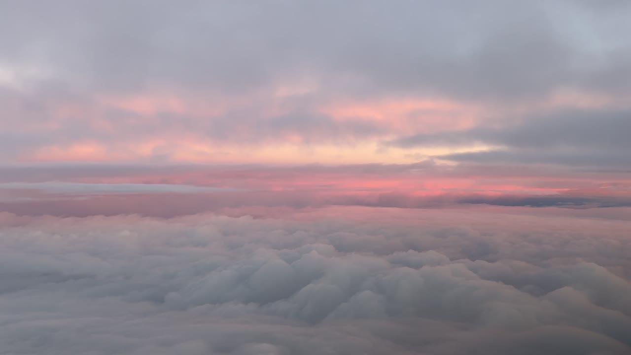 A peaceful flight scene taken from an airplane cockpit while flying between ethereal clouds illuminated by the sunrise light. Handheld camera shot. 4k