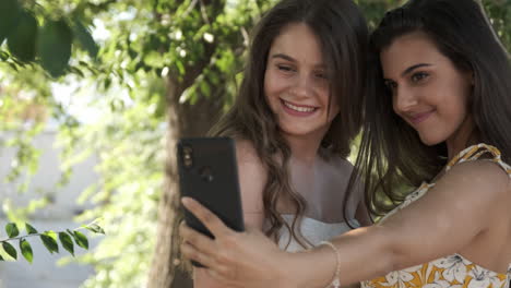 two young women taking a selfie together in a park