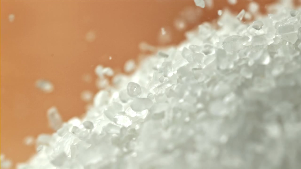 Cristalli bianchi di sale o zucchero che cadono in super slow motion