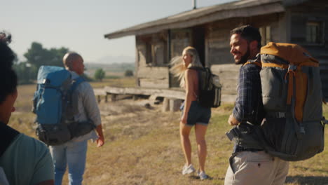 rear view of group of friends with backpacks hiking in countryside together