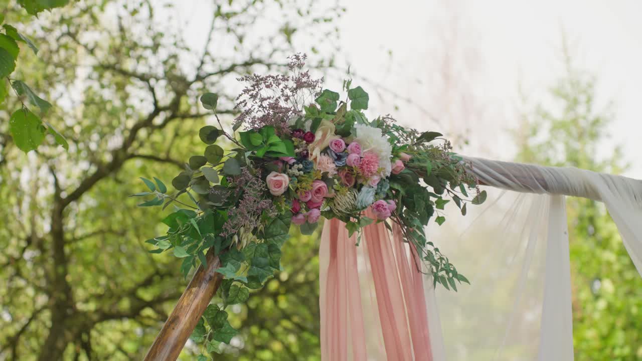 Wedding arch beautifully decorated with flowers standing outdoors surrounded by nature creating a romantic and elegant atmosphere