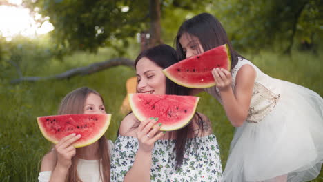 family enjoying watermelon in a park