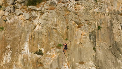 aerial view away from a man rope climbing a steep mountain wall, golden hour