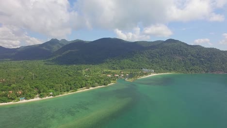 Toma-Aérea-De-Seguimiento-De-Una-Playa-Tropical-En-Koh-Chang-Que-Muestra-Montañas-Con-Una-Selva-Densa-Y-Exuberante-Y-Vistas-Al-Mar