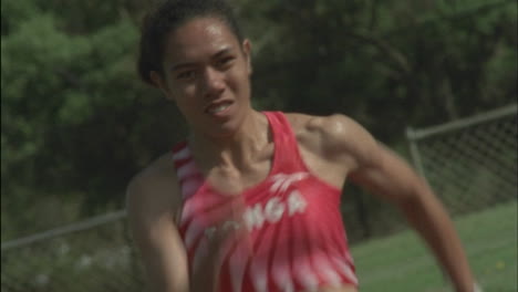 a female athlete runs from a starting block on a track