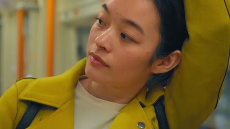 close up of young woman standing on underground train on journey to work or visiting city